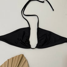 Load image into Gallery viewer, Black bikini top on a white background with a palm leaf