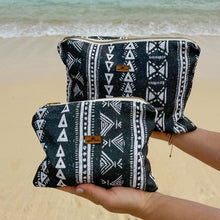 Load image into Gallery viewer, Two black and white patterned pouches held by a person on a beach.