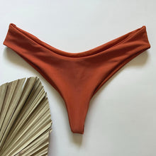 Load image into Gallery viewer, A copper ribbed bikini bottom placed on a white surface, with a dip in the front and ultra cheeky coverage.